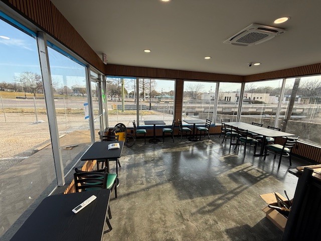 The sunlit seating area inside The Coffee Shop, with green tile, warm wood, and street-facing windows, designed by Buinger Career Academy architecture students.