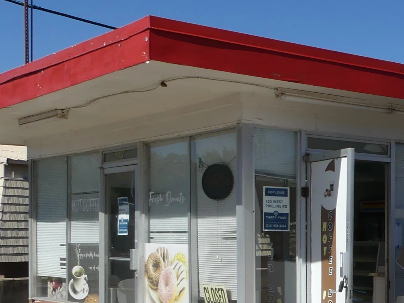 The former donut shop, vacant and up for lease, with a &ldquo;closed&rdquo; sign and faded donut posters still in the windows.